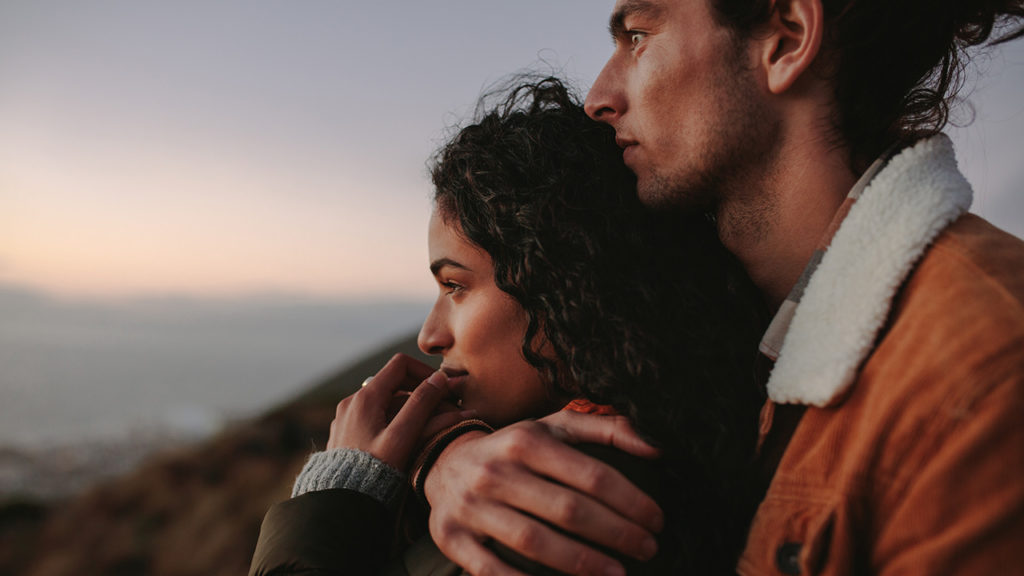 Young man and women hugging each other looking into the distance